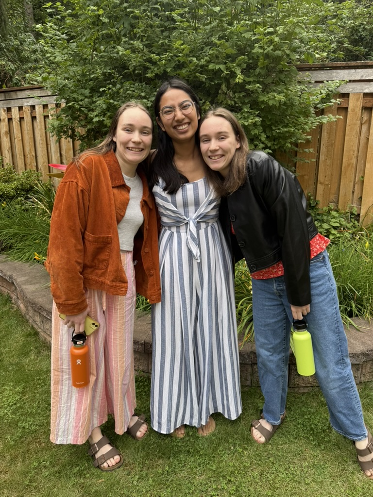 Three girls standing close together outside.