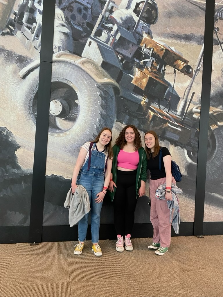 Three girls in front of a Mars rover mural.