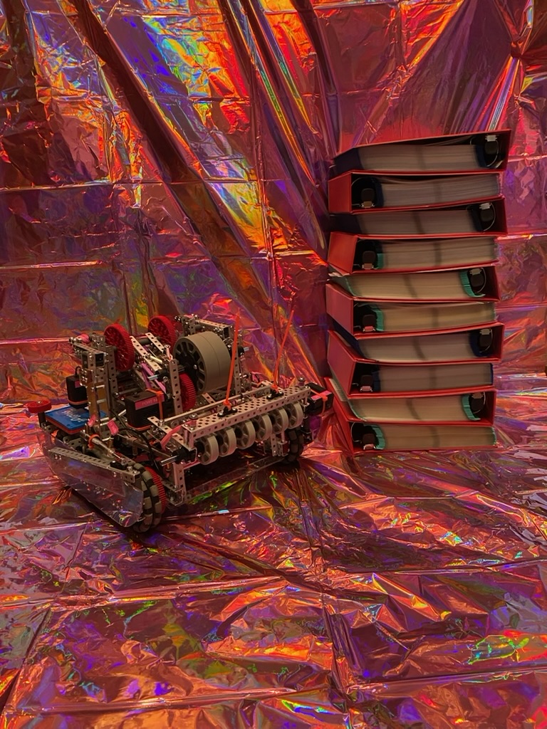 A pink and purple robot in front of a pink sparkly wall next to ten big red binders stacked up.