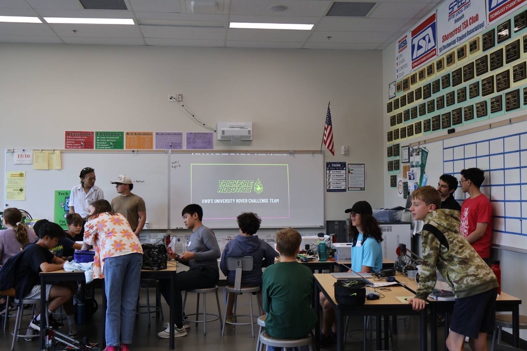Kids standing around tables with robots.