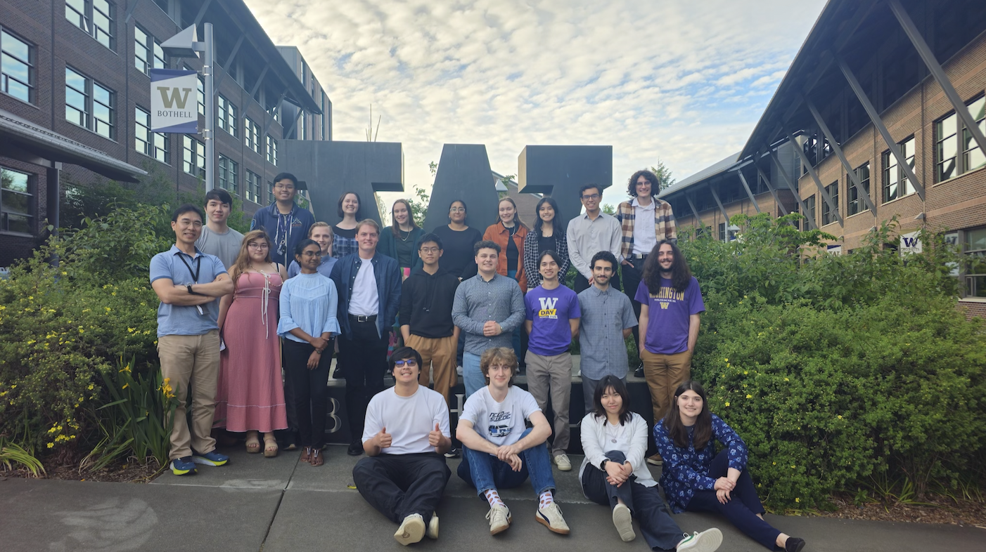 A group of students standing outside in front of a large letter W on a school campus.